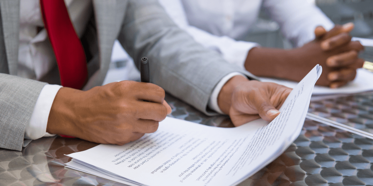 Hand holding a pen, writing on paper.