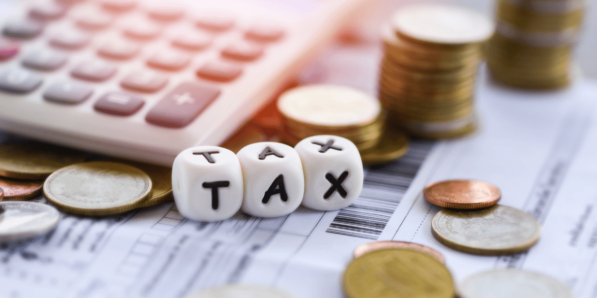Tax written on dices and gold coins with a calculator in a frame.